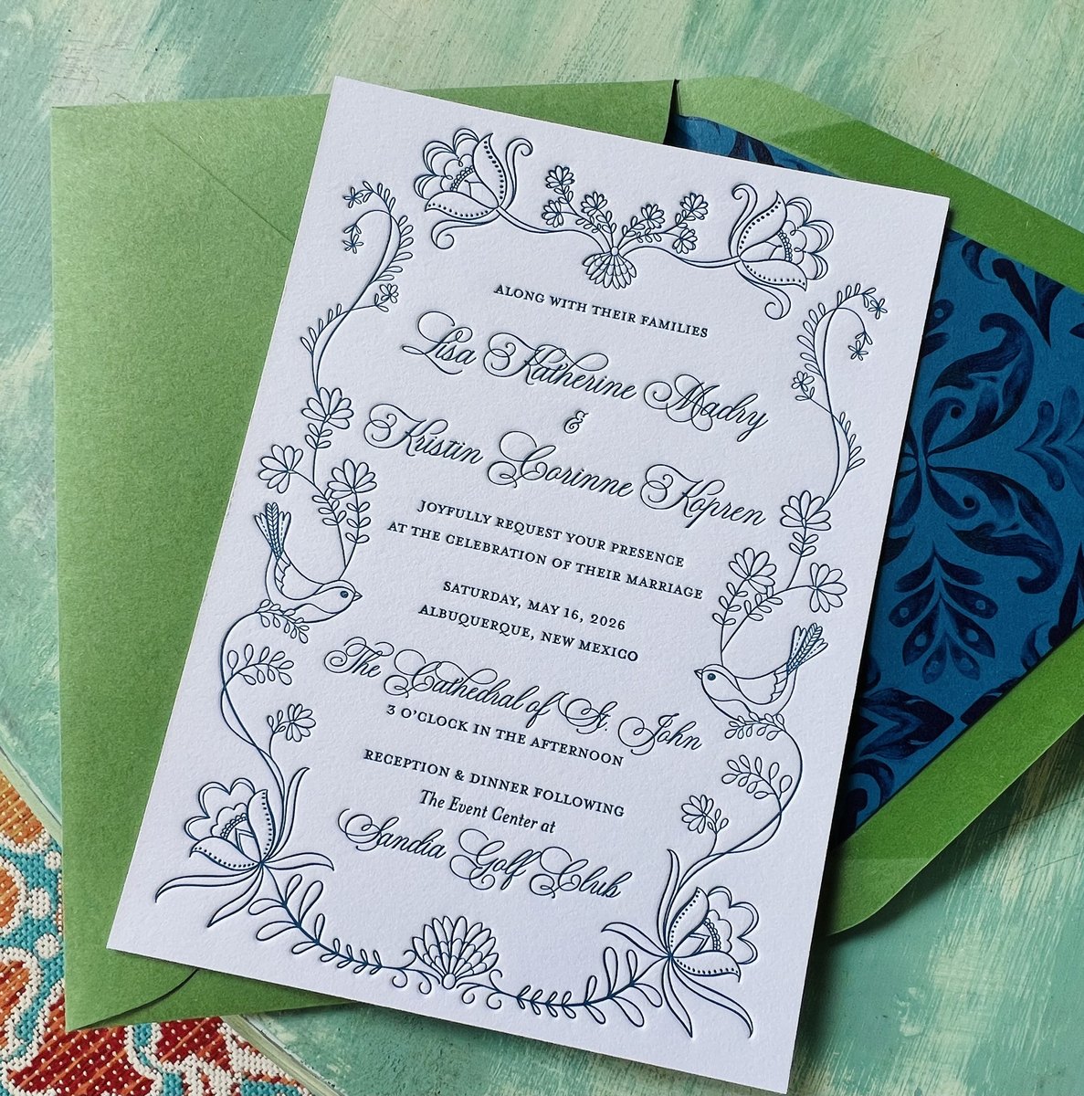 Letterpress wedding invitation in dusty blue line art with doves and wildflowers, with green and blue patterned envelopes, image 2 of 3